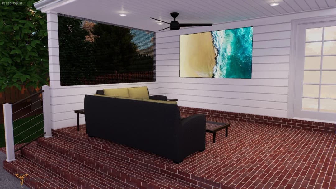 Cozy outdoor patio with a couch, TV, and ceiling fan, featuring a brick floor and greenery.