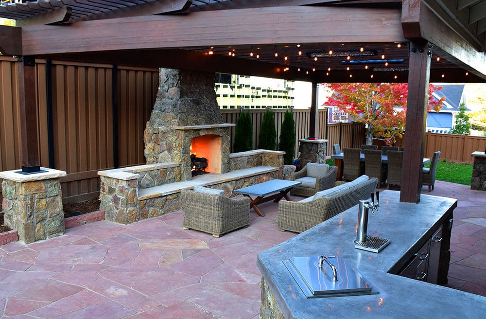 Cozy outdoor patio with stone fireplace, comfortable seating, and a modern outdoor kitchen.