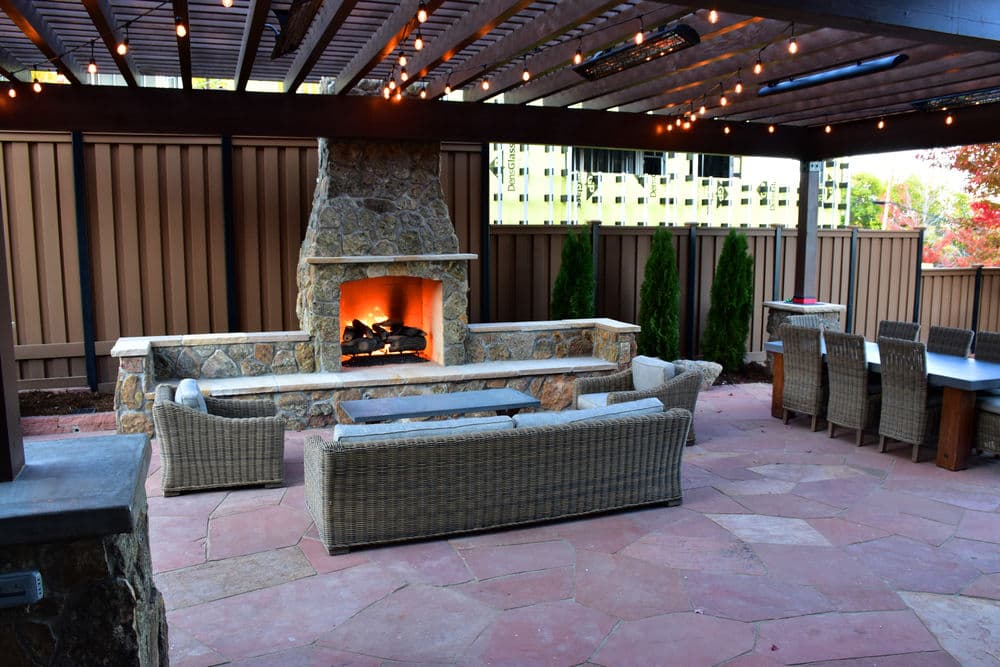 Outdoor patio with stone fireplace, seating area, and string lights for cozy gatherings.