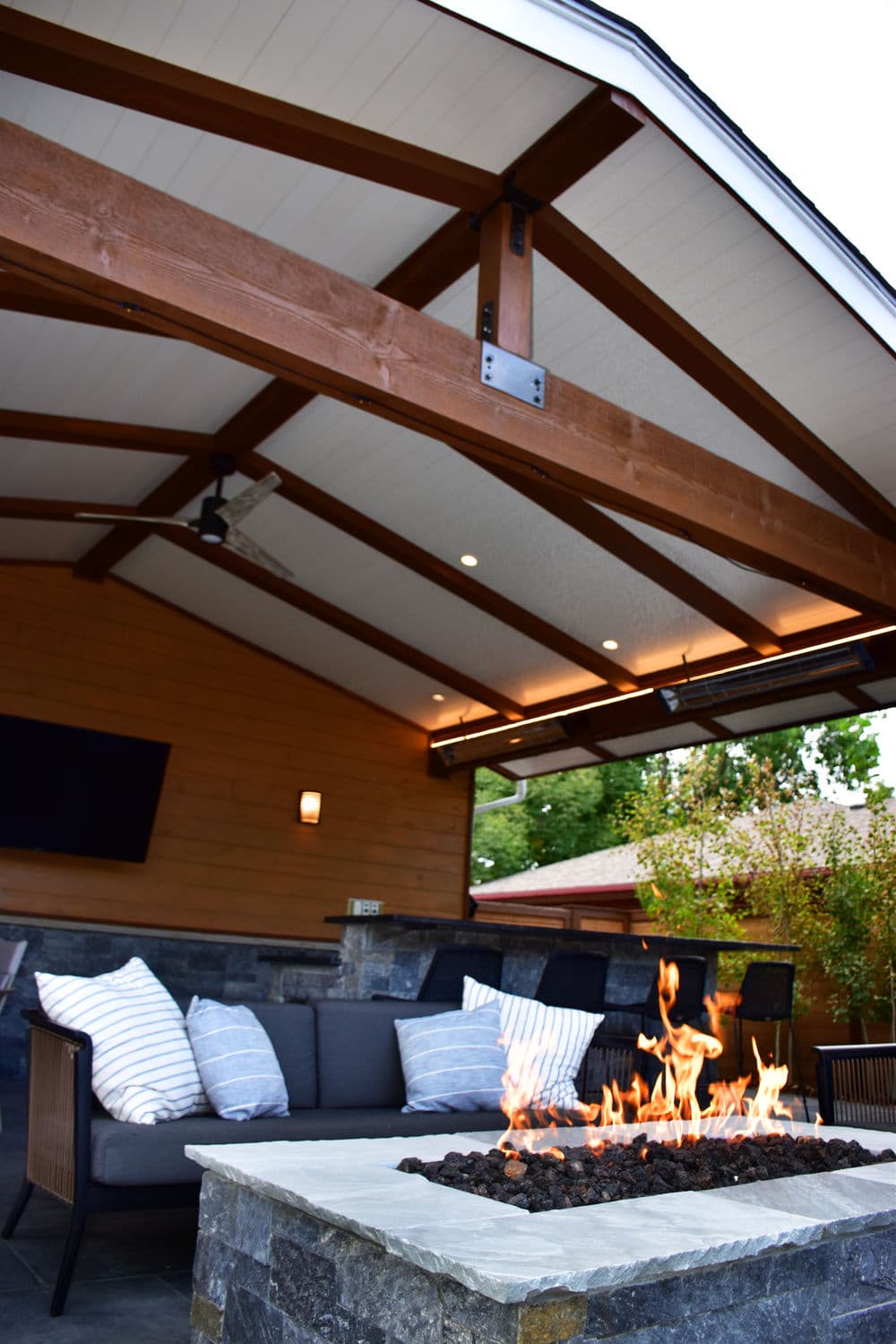 Cozy outdoor patio featuring a fire pit, comfortable seating, and a rustic wooden ceiling.