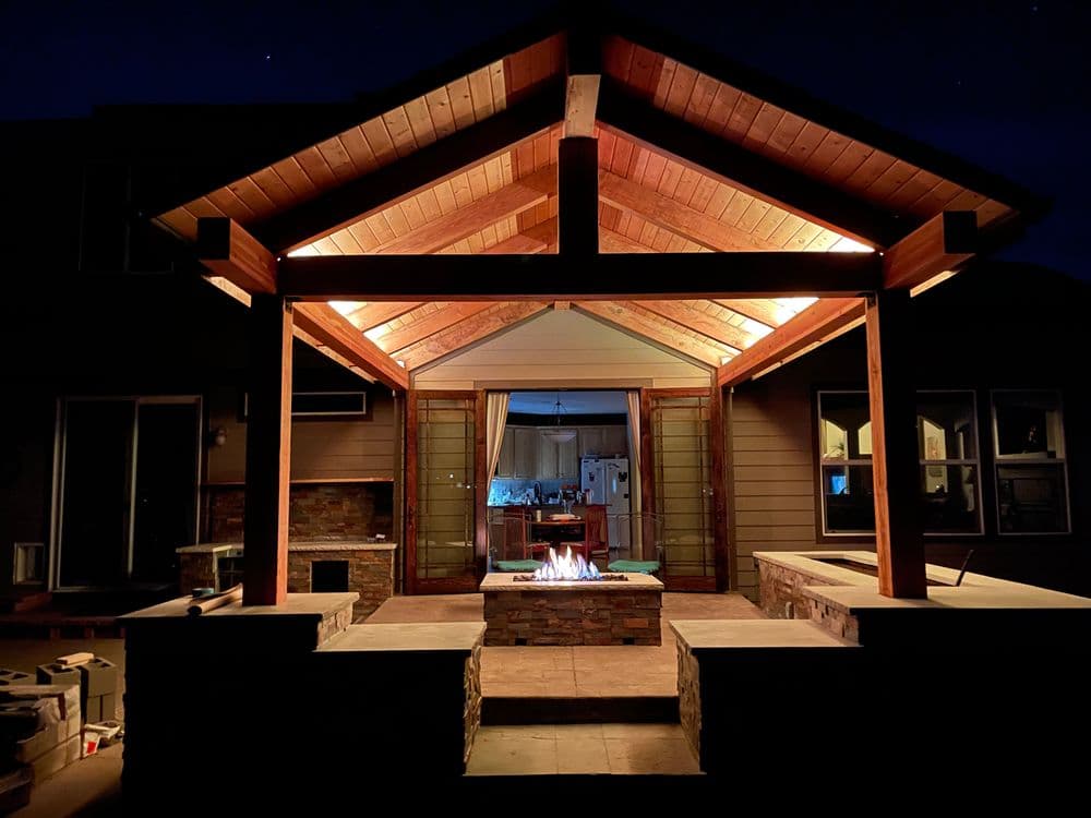 Cozy outdoor living space with a fire pit, illuminated by warm lighting at night.