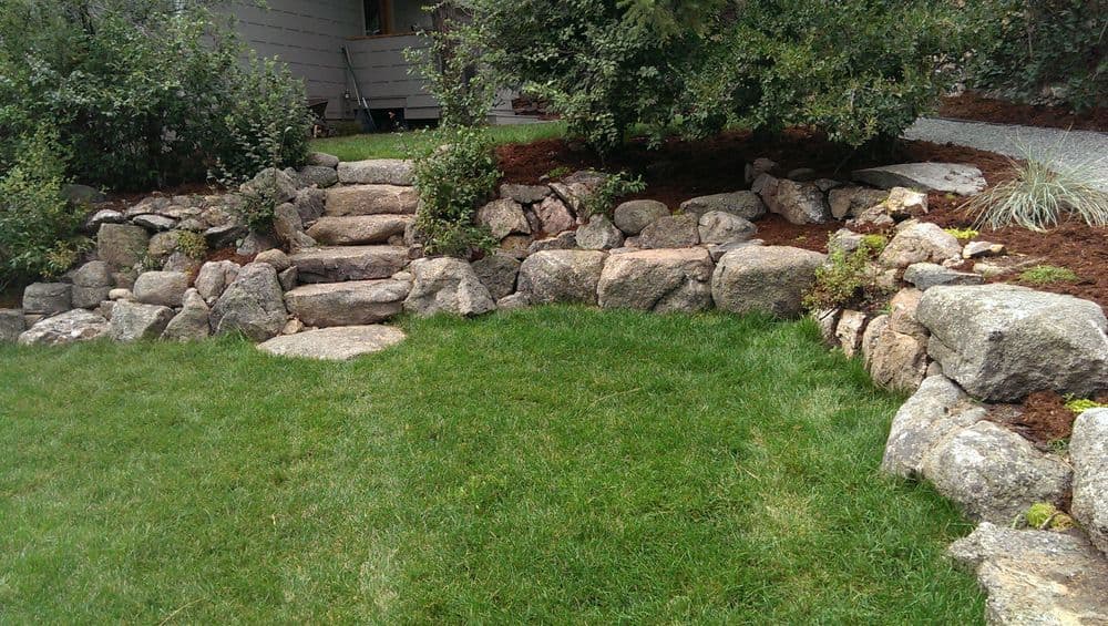 Lush green lawn with stone steps and landscaped rock garden features.