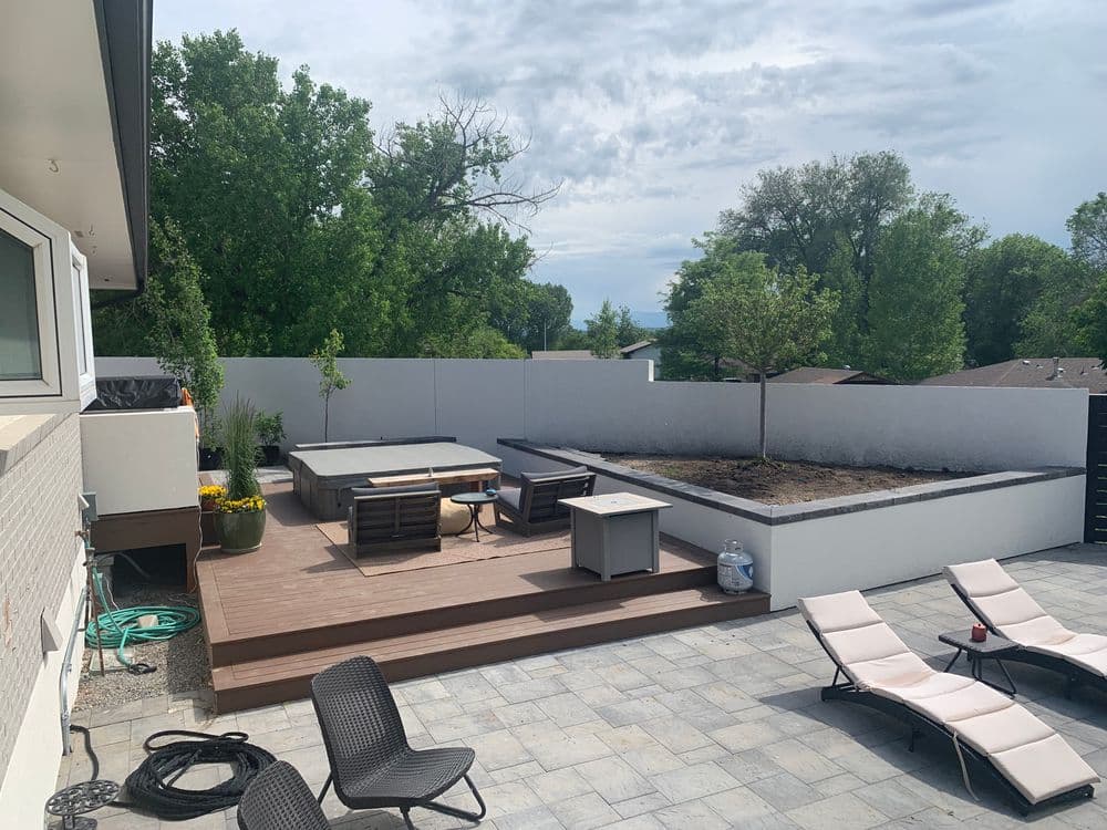 Modern outdoor patio with seating area, planters, and scenic greenery in the background.