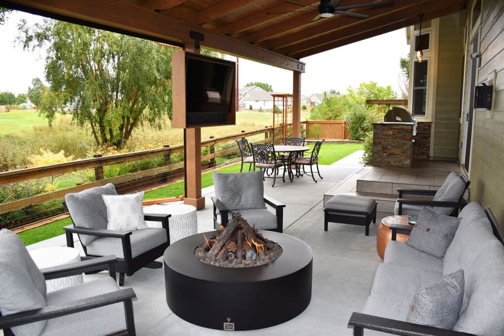 Cozy outdoor living space with fire pit, comfortable seating, and dining area under a wooden patio.