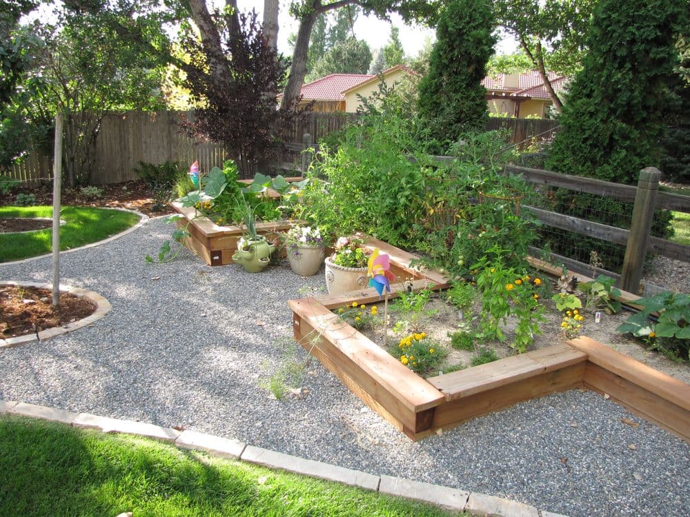 Lush backyard garden with raised beds, colorful flowers, and decorative garden flags.