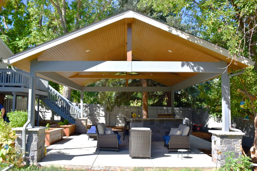 Outdoor patio with a covered gazebo, seating area, and lush greenery in the background.